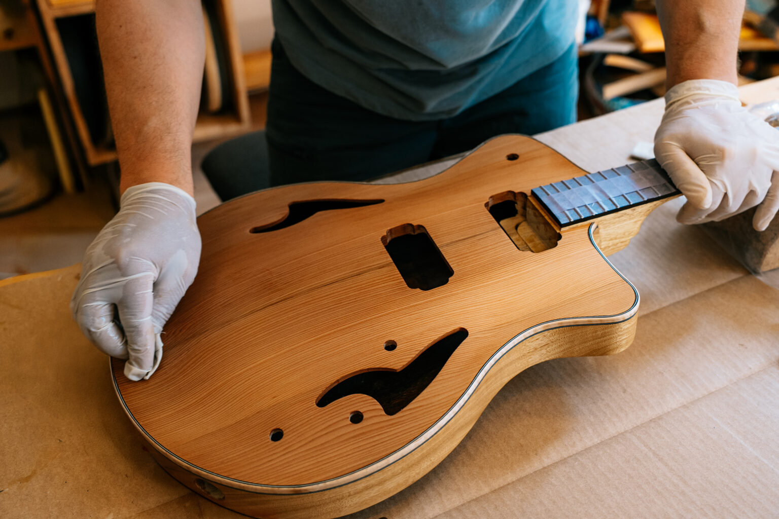 Un luthier vernissant une guitare dans son atelier