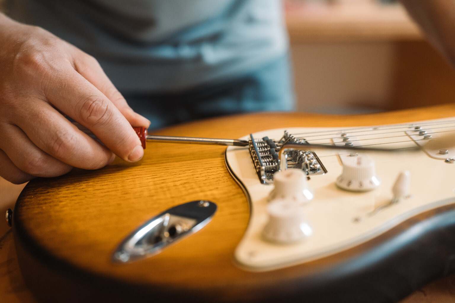 Un luthier accordant une guitare avec un tournevis dans son atelier